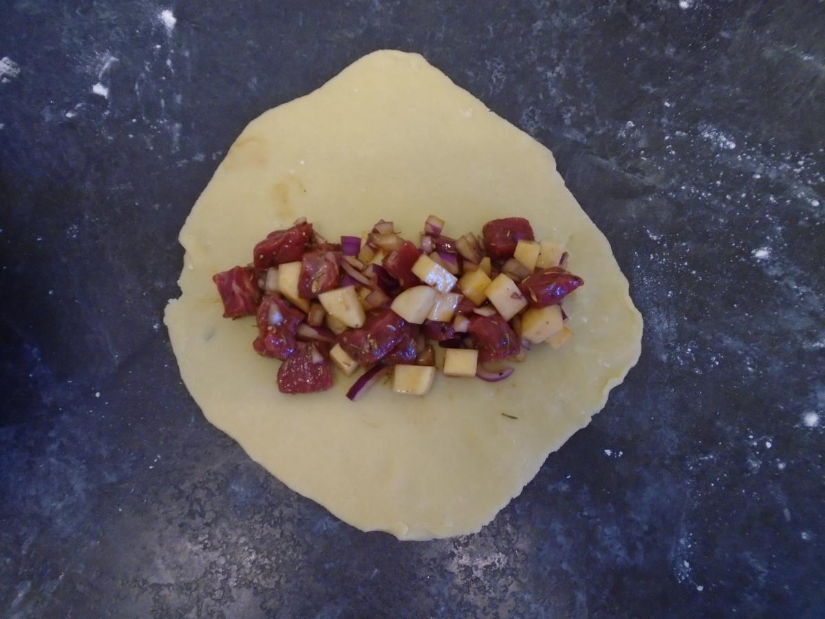 Pile 1/6th of the filling across the middle of the circle then damp the edges of the pastry lightly with water
